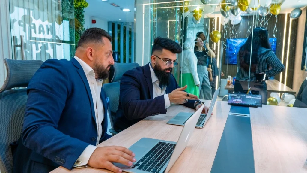 Two men discussing strategy on their laptops