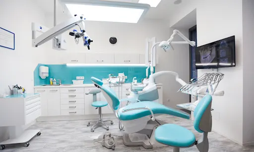 Modern dental clinic treatment room with a teal dental chair and advanced equipment